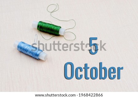Handicraft calendar 5 october. Skeins of green and blue threads for embroidery on beige background. Handmade concept.