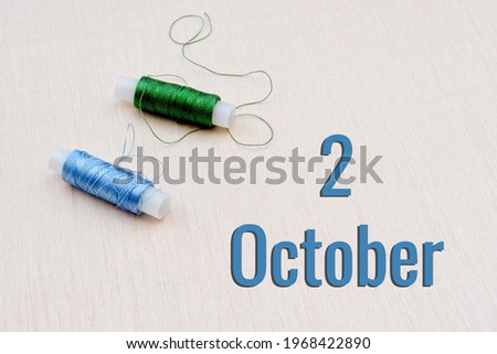 Handicraft calendar 2 october. Skeins of green and blue threads for embroidery on beige background. Handmade concept.