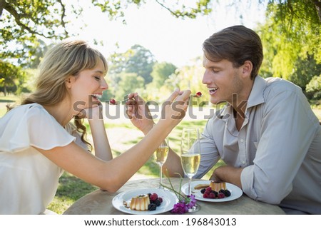 Cute couple feeding each other dessert on a sunny day