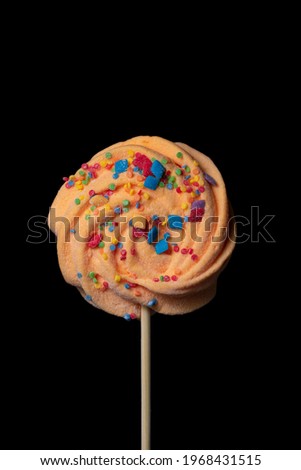 Marshmallow on a stick with multi-colored powder on a black background