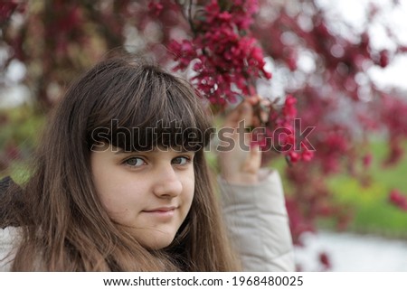 close up smiling caucasian portrait of girl, young woman outdoor, red blossom tree background in the Netherlands