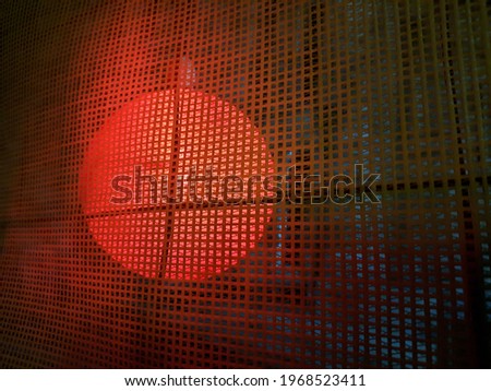 A blurry silhouette of a red round lantern behind a construction grid