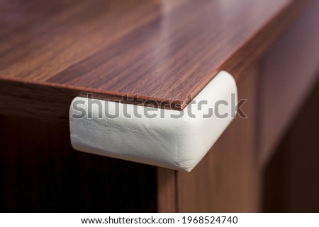 Soft White Edge Protector On A Wooden Desk Corner - Prevent Child Hazard Concept