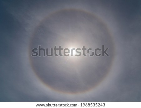 Sun halo caused by the refraction, reflection, and dispersion of light through ice particles suspended within thin, wispy, high altitude cirrus or cirrostratus clouds. Royalty-Free Stock Photo #1968535243