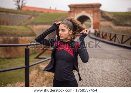 one young woman, adjusting pony tail, runner.