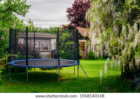 Dough trampoline in the garden near the flowering wisteria. Royalty-Free Stock Photo #1968540148
