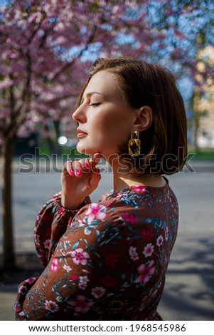 Portrait of a cute and beautiful woman girl in a dress in the garden in the middle of blooming sakura. spring and sun time. Blurred background and selected focus.
