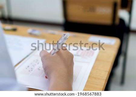 Education school test concept : Hands student holding pencil for testing exams writing answer sheet or exercise for taking fill in admission exam multiple carbon paper computer at university classroom Royalty-Free Stock Photo #1968567883