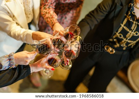 Close up on hands of unknown women holding a glasses of red wine toasting