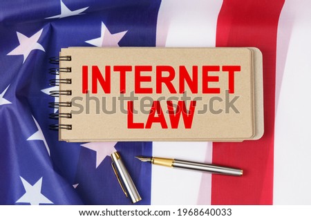 Law and order concept. Against the background of the flag of the United States of America lies a notebook with the inscription - INTERNET LAW