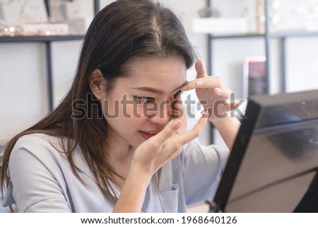 Asian young woman putting contact lenses at optical shop, trying on new contact lenses Royalty-Free Stock Photo #1968640126