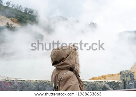 A woman wearing a mask is taking pictures in the "Kawah SiKidang" Dieng.