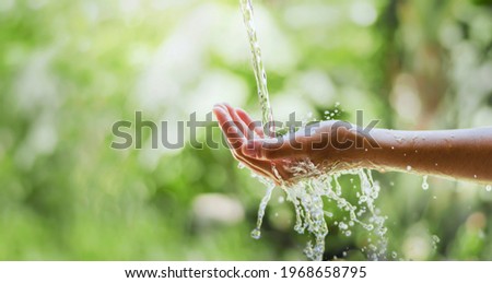 water pouring flow on woman hand on nature background Royalty-Free Stock Photo #1968658795