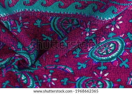red silk fabric with blue patterns of flowers circles. Charmeus has a beautiful drapery. It can be assembled in soft fullness. Background