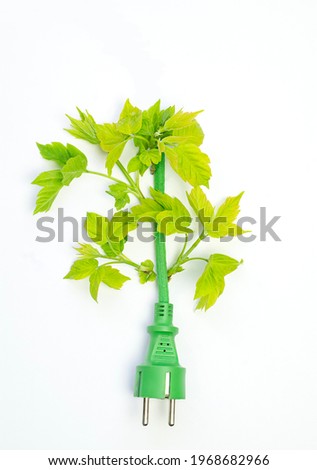 Green electric plug with green leaves on a white background, ecology concept, copy space. High quality photo