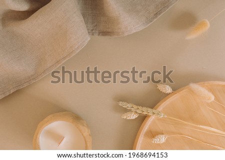 Neutral trendy background with linen napkin, wooden tray, candle and decorative dried grass. Business branding, blog, social media template. Copy space mockup.