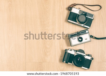 SLR camera, rangefinder camera and compact camera on wooden background