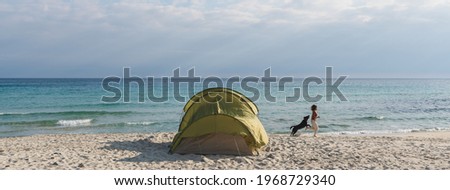 Horizontal banner or header Camping tent on the beach and woman at distance running on the shore with her dog