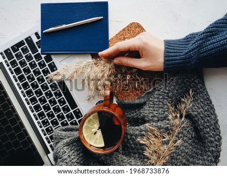 Flat lay with a picture of a woman's hand, a notebook, a mug, lemon tea, a pen, flowers. 
