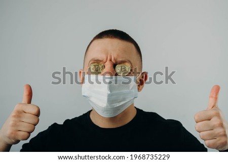 The guy in the protective mask has bitcoins instead of eyes. Coronovirus and Bitcoin. Cryptocurrency.