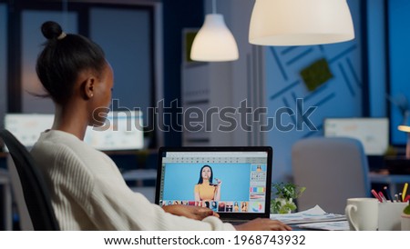 African professional woman photo retoucher working on laptop at new project in business office at night time. Content creator doing portrait retouching, artist, occupation, screen, graphic