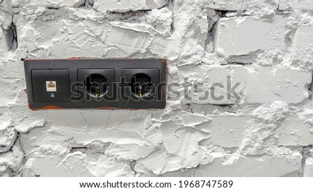 White brick wall with black electrical outlets.