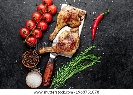 Roasted duck leg with spices on a knife on a stone background