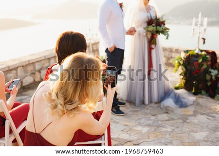 Guests at the wedding ceremony filming the bride and groom on the phones  Royalty-Free Stock Photo #1968759463
