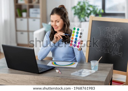 distant education, school and people concept - female teacher with laptop computer and colors having online class of arts at home