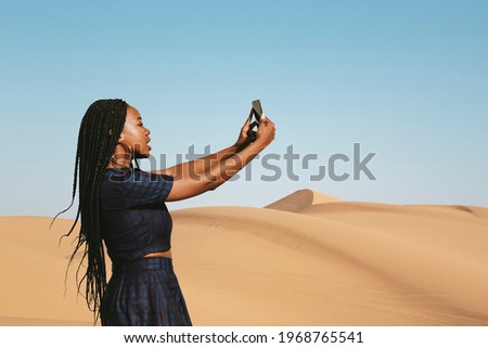 Black woman taking a photo on a desert