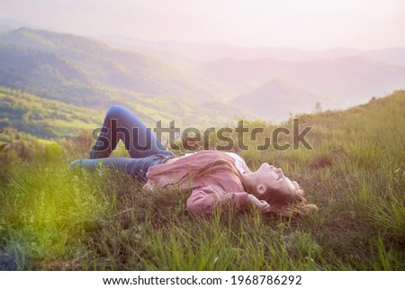 Beautiful girl lies and rests at the precipice the top, Slavic appearance, Slavonic woman on the top of mountains, hiking enjoying moment, nature, traveling tourism. The Carpathians mountains.