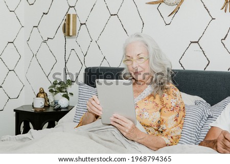 Elderly woman using a tablet in bed
