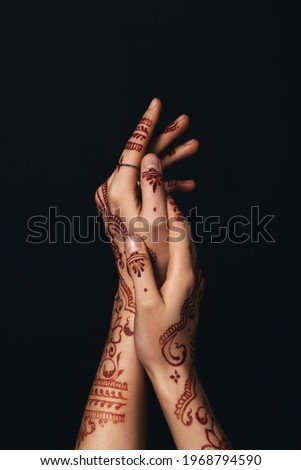 Beautiful female hands with henna tattoo on dark background
