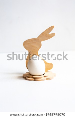 colored figurine - a stand made of wood in the form of a hare inside which an egg on a white background