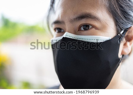 Asian lady woman wearing cloth mask on a surgical mask,people puts double or two masks on her face for COVID-19 protection, prevent Coronavirus infection,safety from air pollution,health care concept