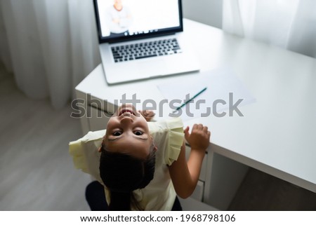 Litttle girl looking at laptop screen with expression of surprised and excitement. Smart, smilling little girl taking notes . Communication in business concept.