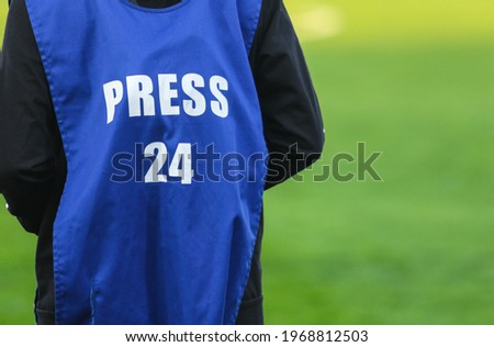 Blue shirt of a photographer during a football match