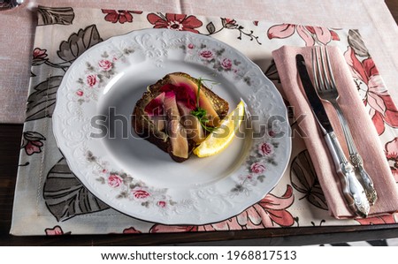 festive kitchen table setting and food with drinks and beautiful red-green tablecloths with flower patterns. Shrimp sandwich, herring sandwich, tomato juice, lemon, herbs,, a vase of flowers. Tableclo