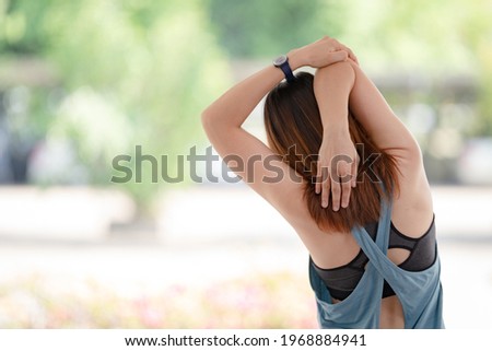 Young beautiful Asian woman in sports outfits doing stretching before workouts at hot during COVID-19 pandemic to keep a healthy life. Healthy young woman stretching and warming up to workouts