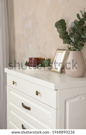 Modern chest of drawers with decor near beige wall