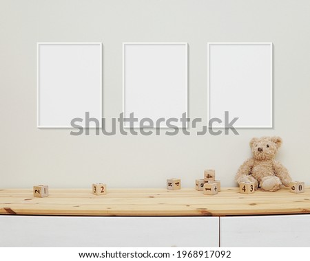 3 blank vertical frames mockup on wall for nursery wall art display, baby room three white frames, wooden shelf, soft toys.