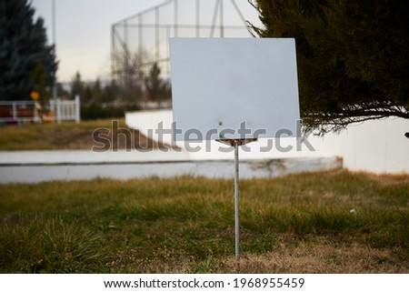 a white sign with a blank space for text on the green lawn.