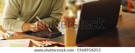 Cropped shot of a man drawing illustration on his graphic tablet. Artist using digital tablet to draw illustrations at home. Royalty-Free Stock Photo #1968956053