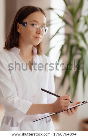 Stock Photo - Lab assistant woman in glasses makes notes in a notebook