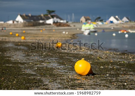 Orange buoy lying on the beach at low tide, cloudy day in summer, Brittany (France)