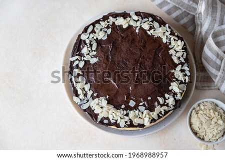 Delicious creamy cheesecake decorated with chocolate glaze and almond, light concrete background. No bake mousse dessert. Selective focus.