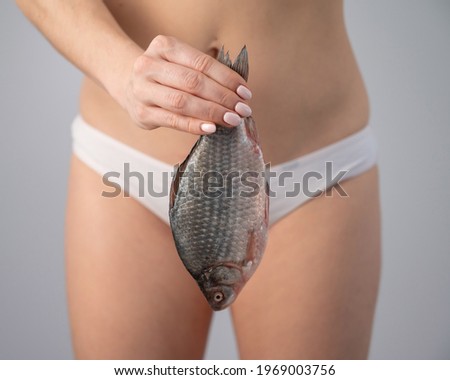 A woman in shorts is holding a fish. Feminine hygiene and health concept.
