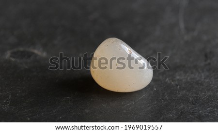 White chalcedony tumbled pebble on gray slate background  Royalty-Free Stock Photo #1969019557