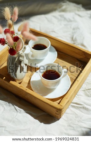 Breakfast in bed, try with two cups coffee and flower in sunlight at home, chambermaid bringing tray with breakfast in hotel room, good service