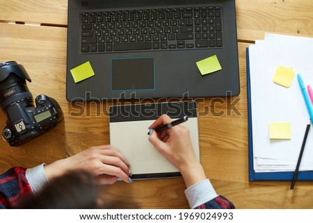 Creative female photographer, using graphic drawing tablet and stylus penCreative female photographer, using graphic drawing tablet and stylus pen